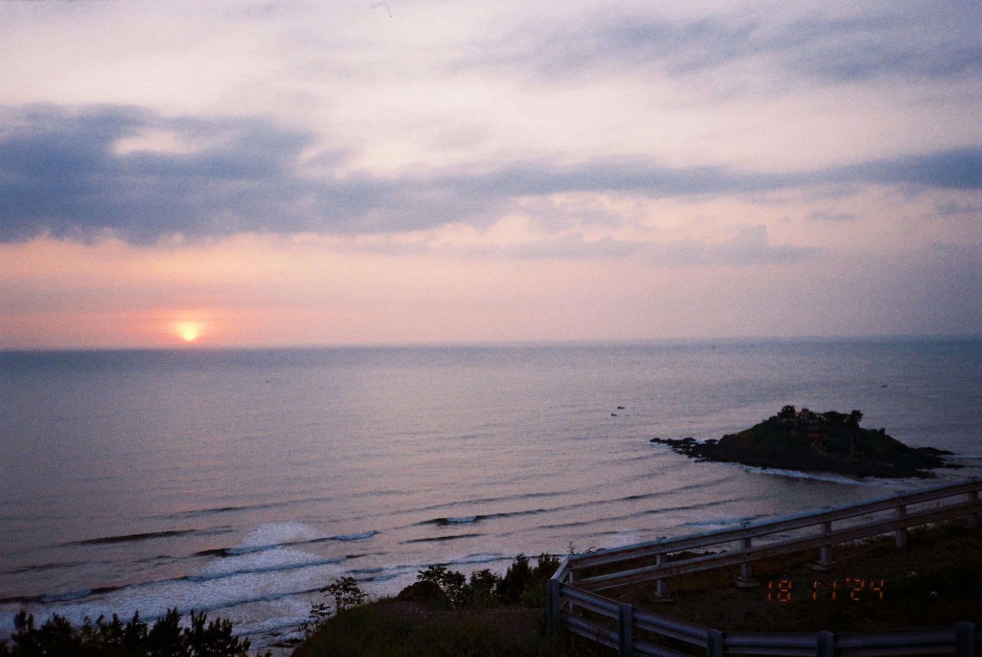 Peaceful sunset over the ocean with a view of a coastal landscape and calm waters.