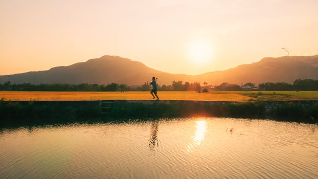 A man jogs by a scenic landscape in Quy Nhơn, Vietnam, at sunset.