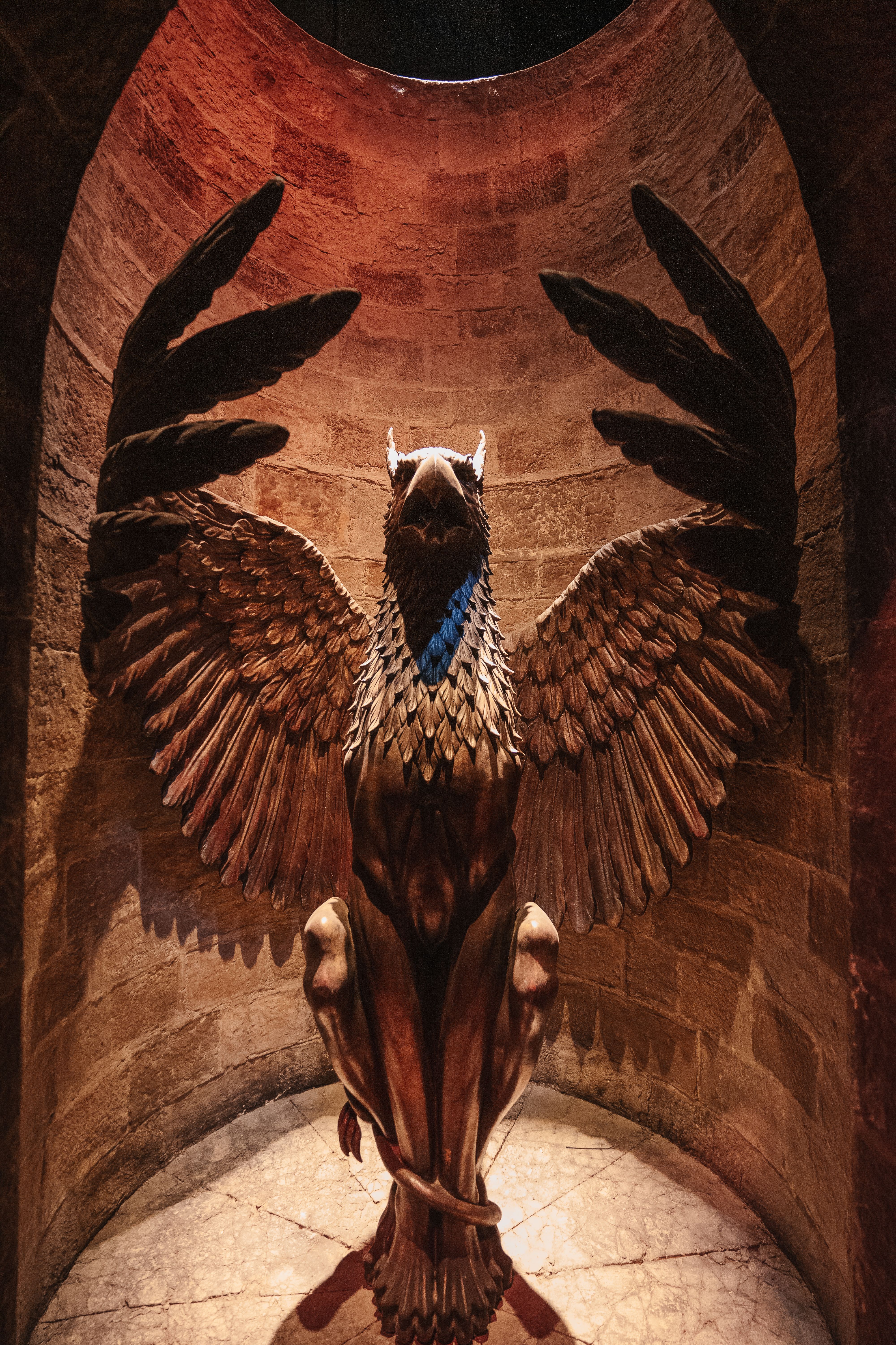 A dramatic winged statue set in a stone alcove with warm lighting.
