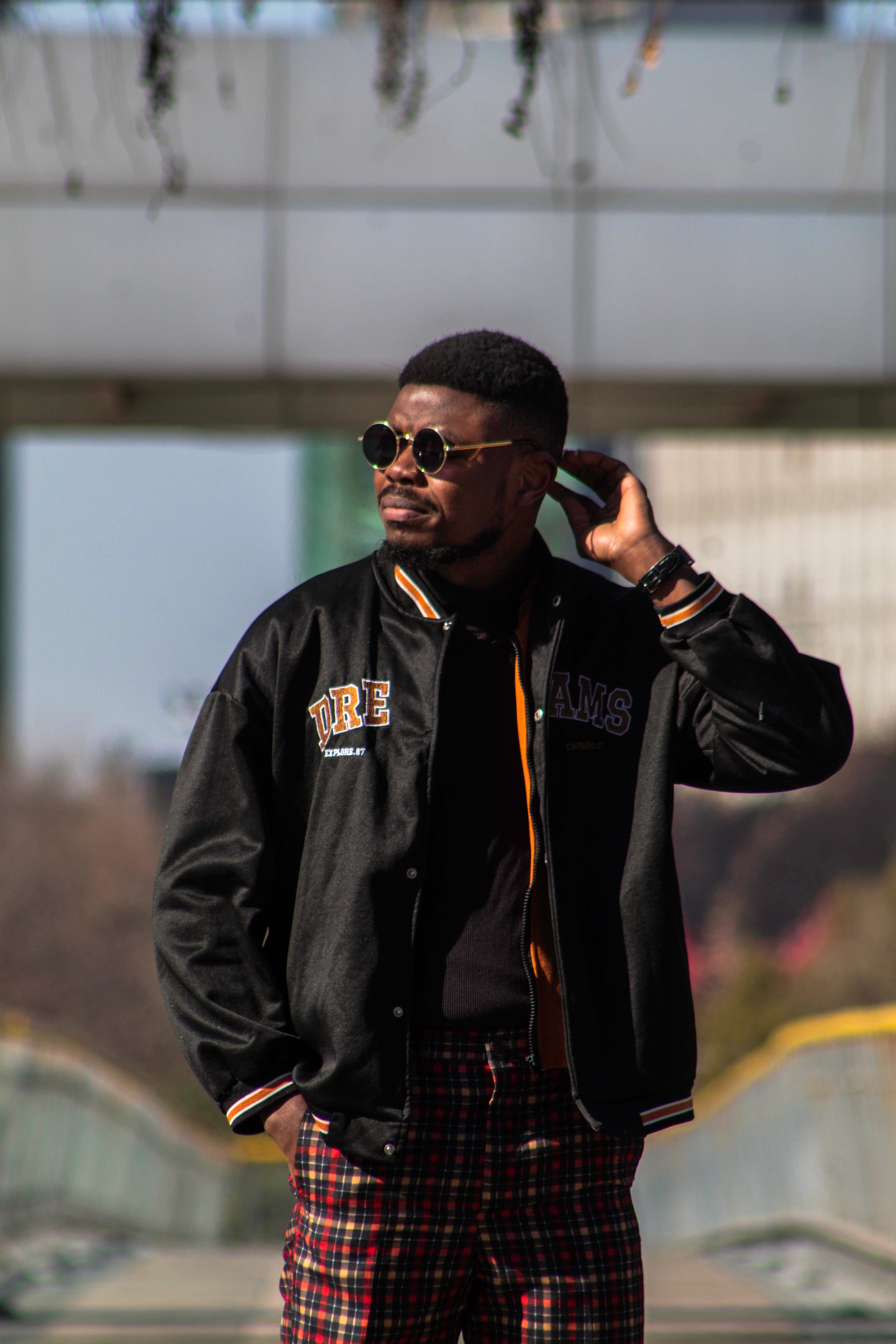 Confident man with sunglasses in urban area wearing trendy fashion.