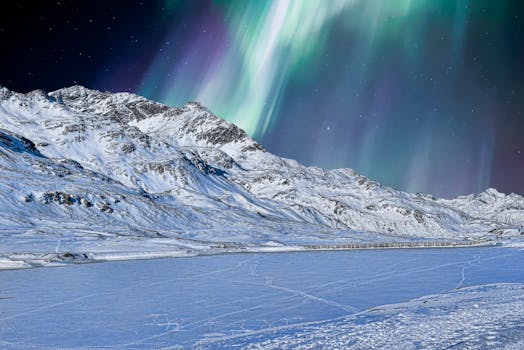 A stunning winter scene with snowcapped mountains and the aurora borealis in the night sky.