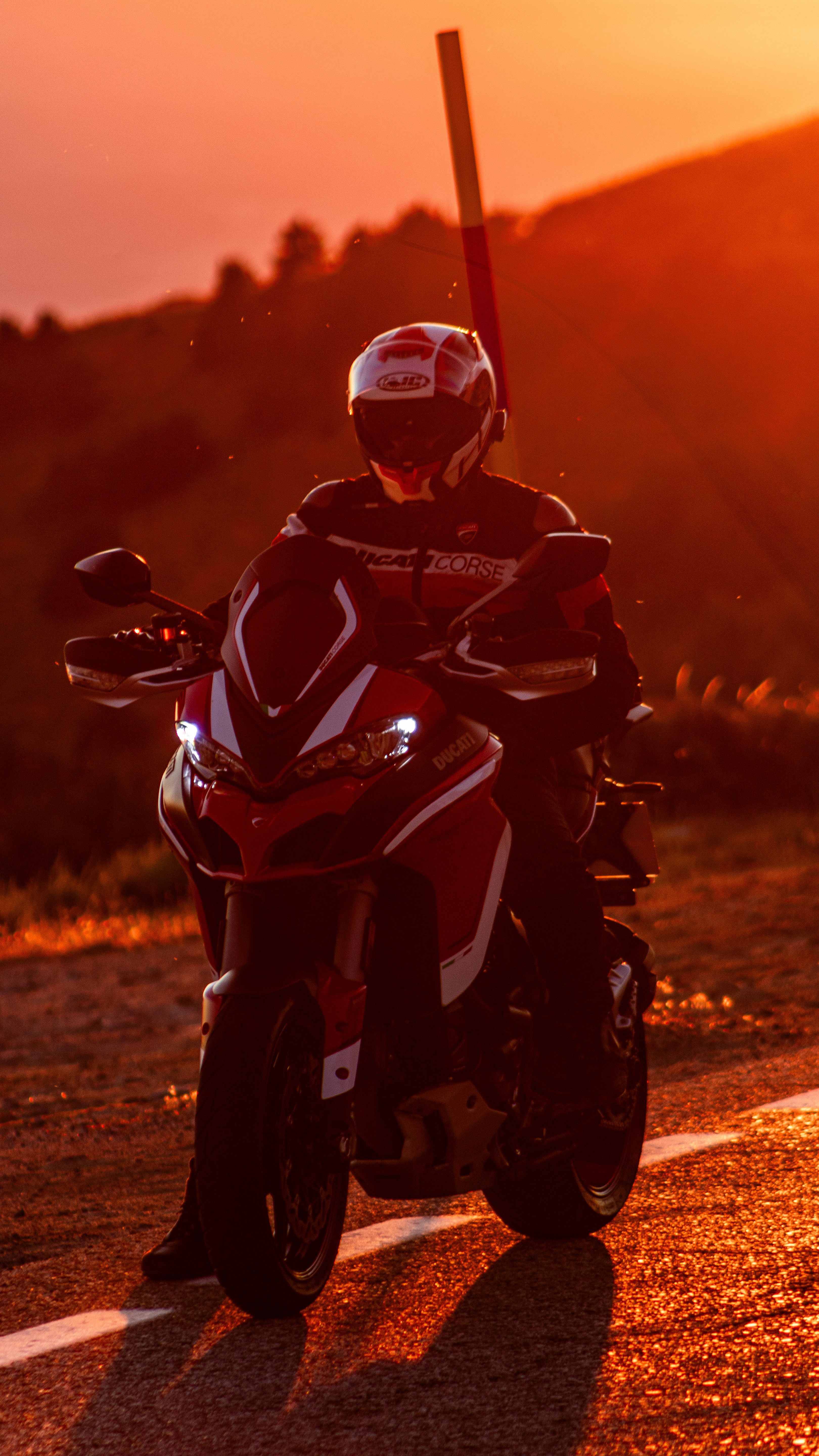 Adventure motorcyclist riding into the sunset on a mountain road