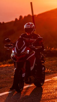 A biker on a red sports motorcycle enjoying a sunset ride on a scenic mountain road.