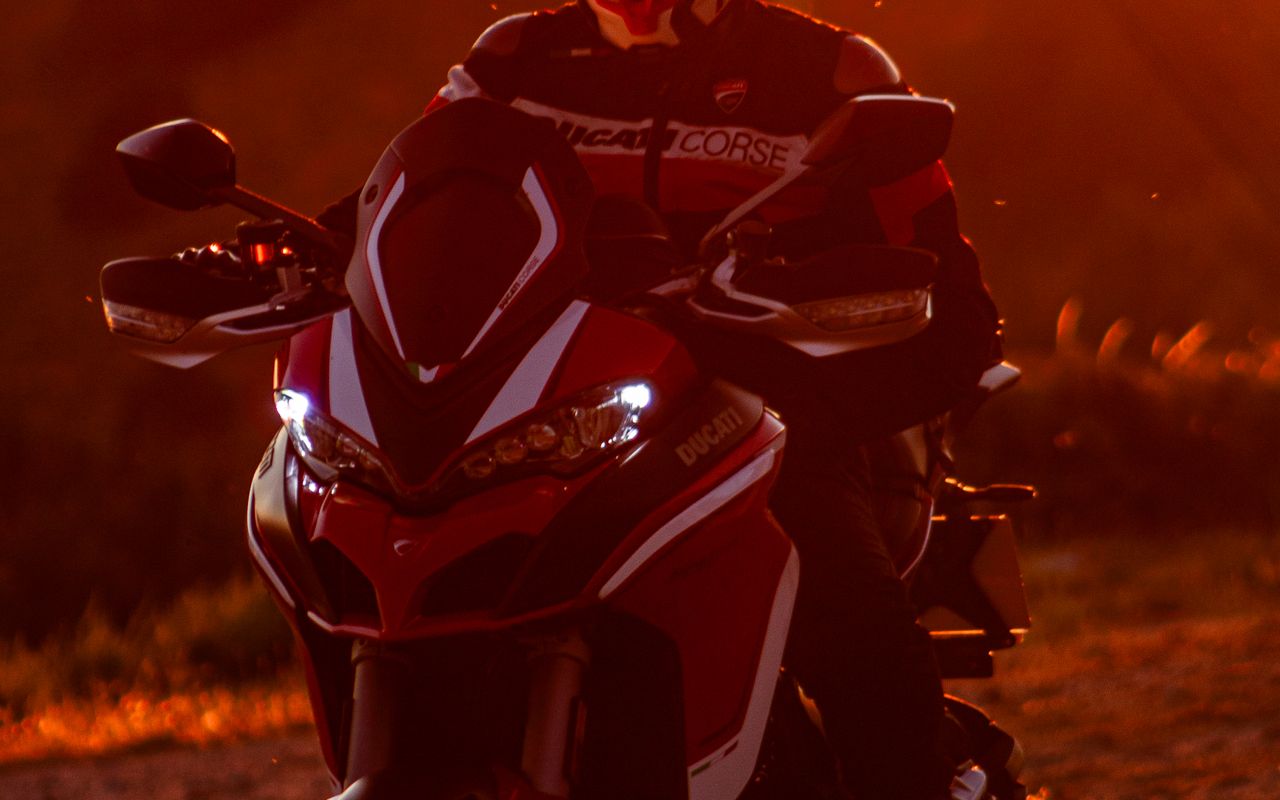 Adventure motorcyclist riding into the sunset on a mountain road