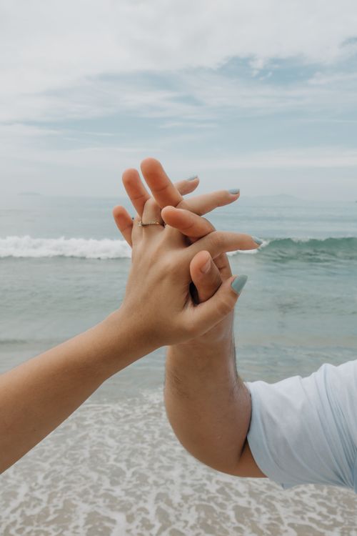 Free Close-up of a couple holding hands by the ocean at Ubatuba Beach, São Paulo. Stock Photo