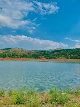A scenic view of a tranquil lake with distant mountains and clear blue sky.
