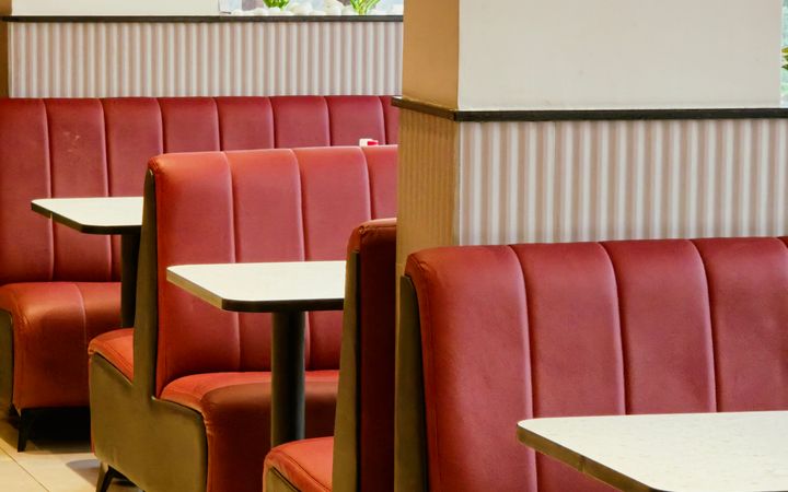 Empty diner interior with red booth seating and natural lighting. Ideal for cozy dining.