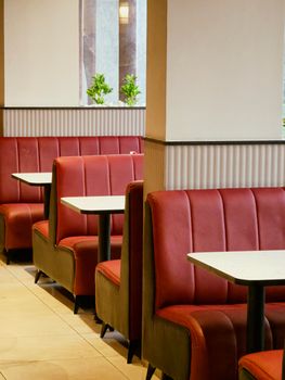 Empty diner interior with red booth seating and natural lighting. Ideal for cozy dining.