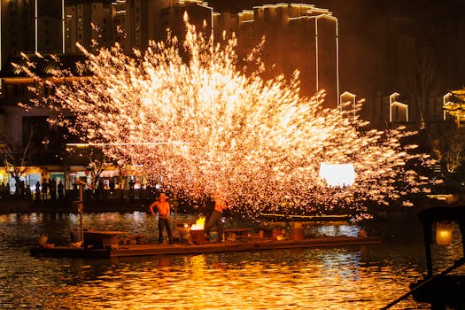 Splendenti fuochi d'artificio illuminano il cielo notturno sopra un fiume, dando risalto alle celebrazioni culturali.