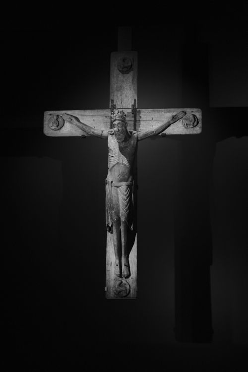Free Monochrome photo of a detailed crucifix sculpture against a dark background. Stock Photo