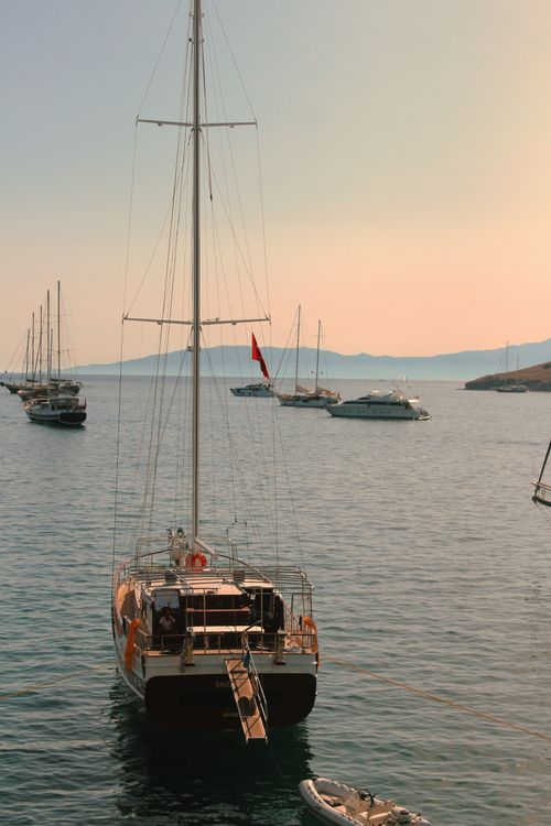 Free A peaceful scene of sailboats docked in calm waters at sunset. Stock Photo
