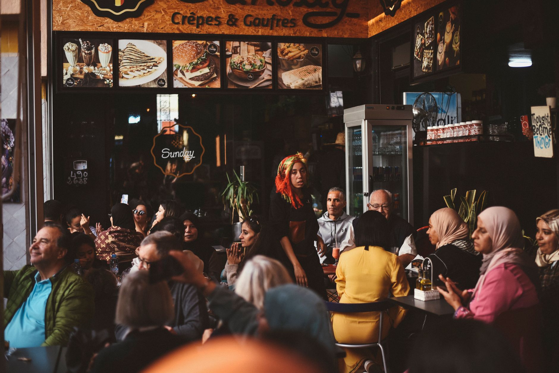Lively atmosphere in a bustling Agadir cafe with diverse group of people enjoying their time.