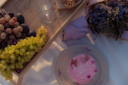 A charming picnic scene with grapes, flowers, and a cake reading 'Feeling 22'. Perfect for celebrations.