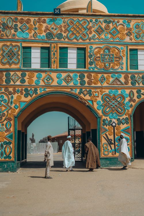 Free A vibrant traditional African building with intricate designs and people walking through the entrance. Stock Photo