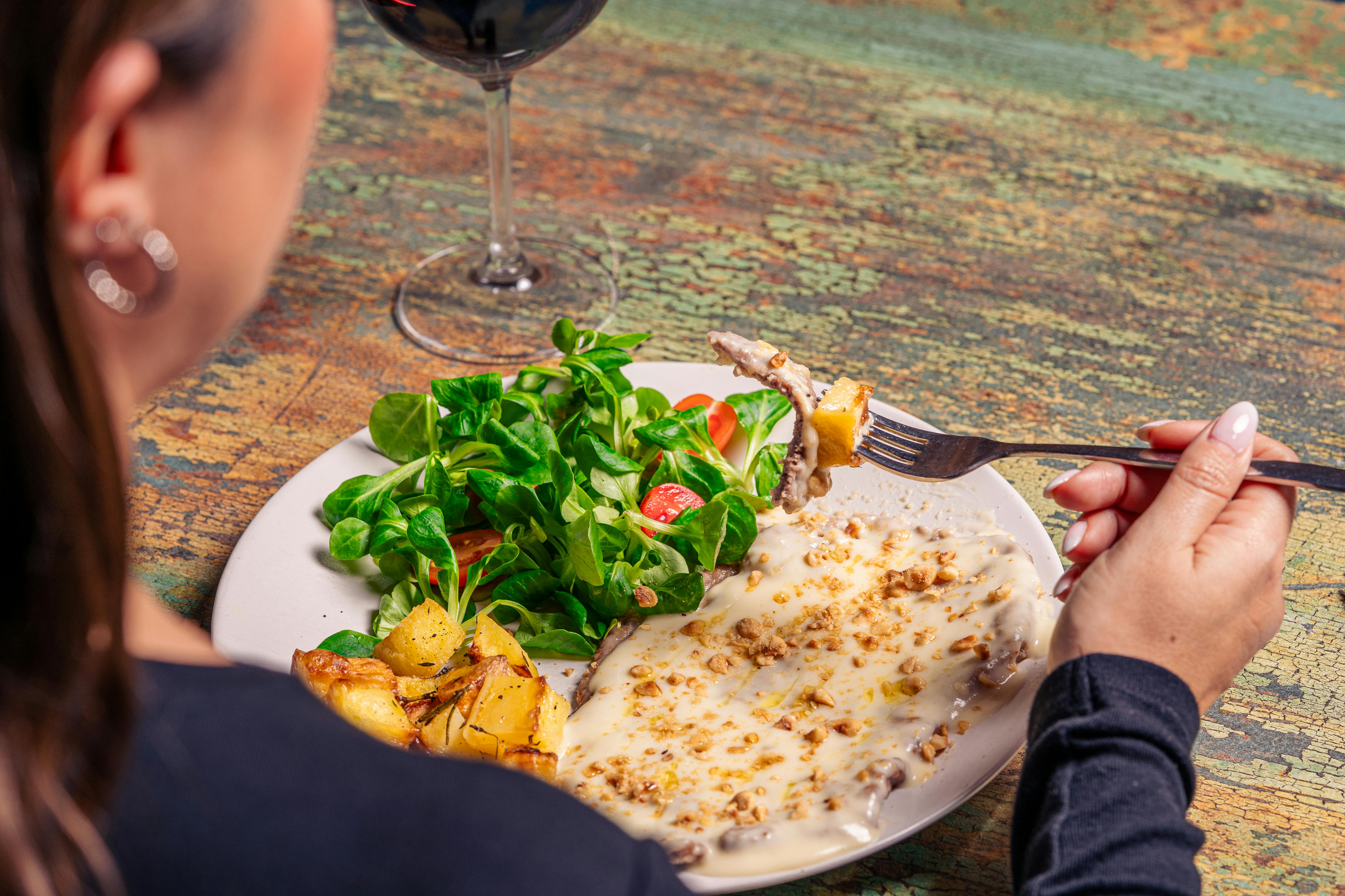 Overhead shot of woman enjoying a salad and potato dish with wine