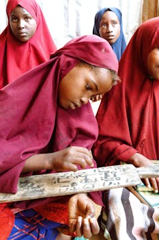 Young girls studying with traditional writing tablets in a classroom setting.