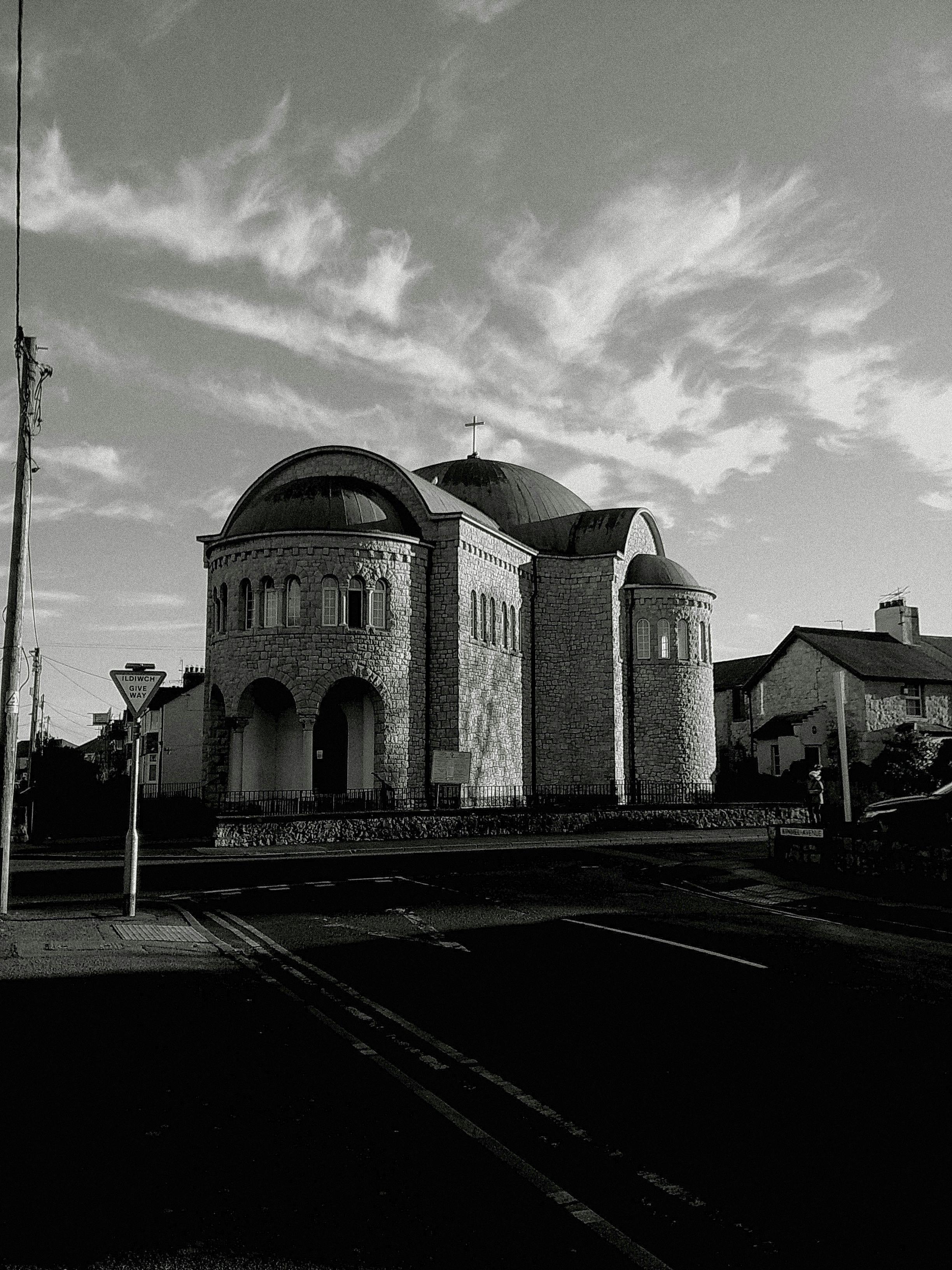 A striking black and white photo of a stone church with a dramatic cloudy sky.