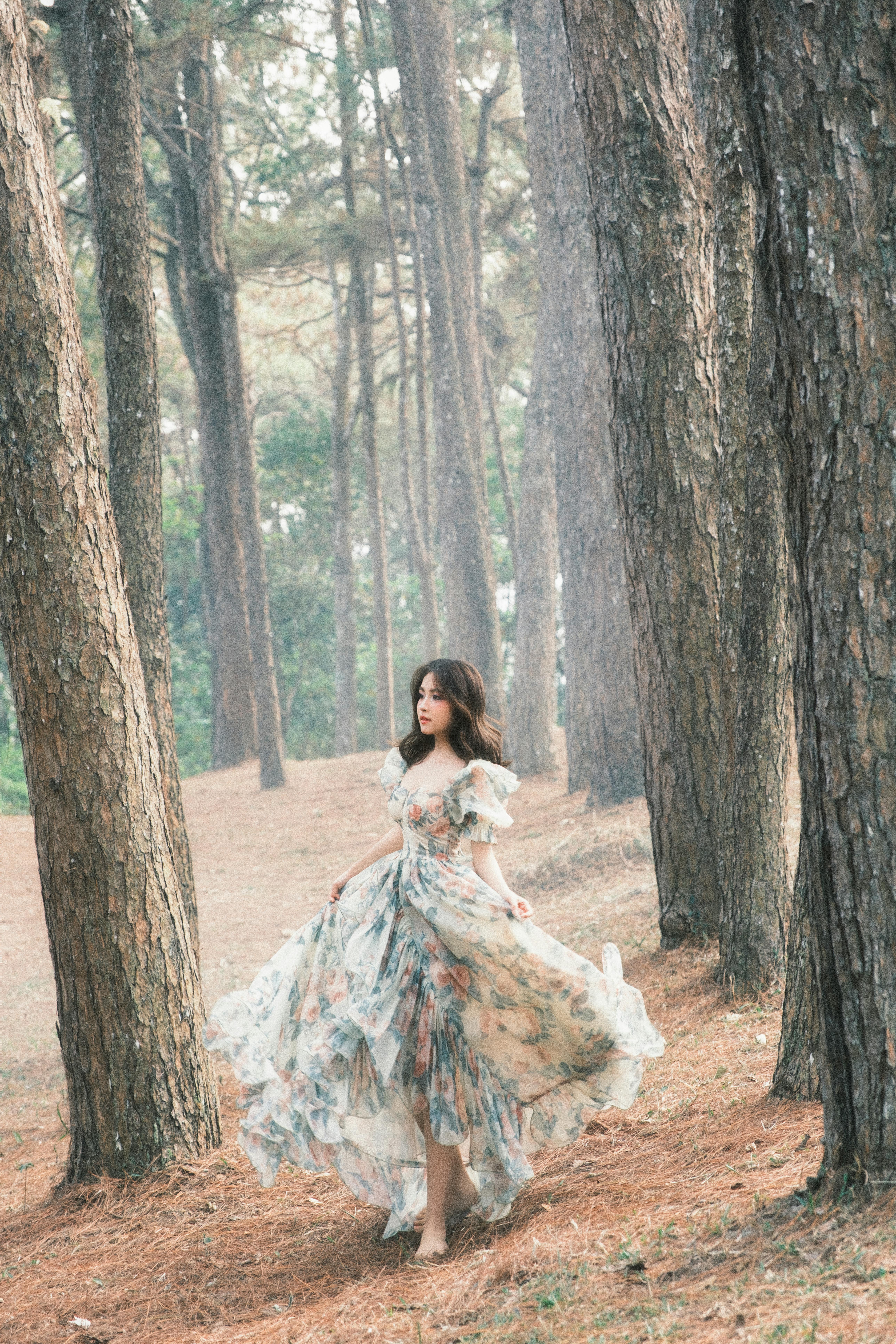 A woman in a floral dress walking gracefully through a serene forest.