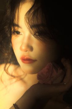 Dreamy portrait of a woman holding a rose, captured in soft lighting.