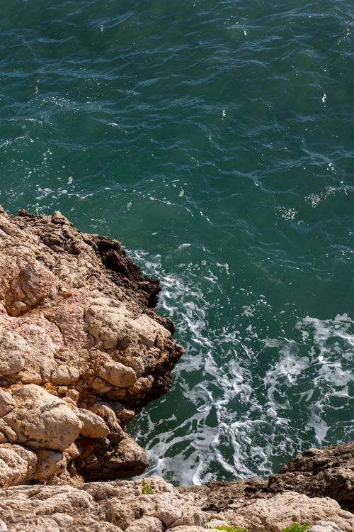 Free Stunning view of a rocky cliff meeting the Mediterranean Sea in Sitges, Spain. Stock Photo