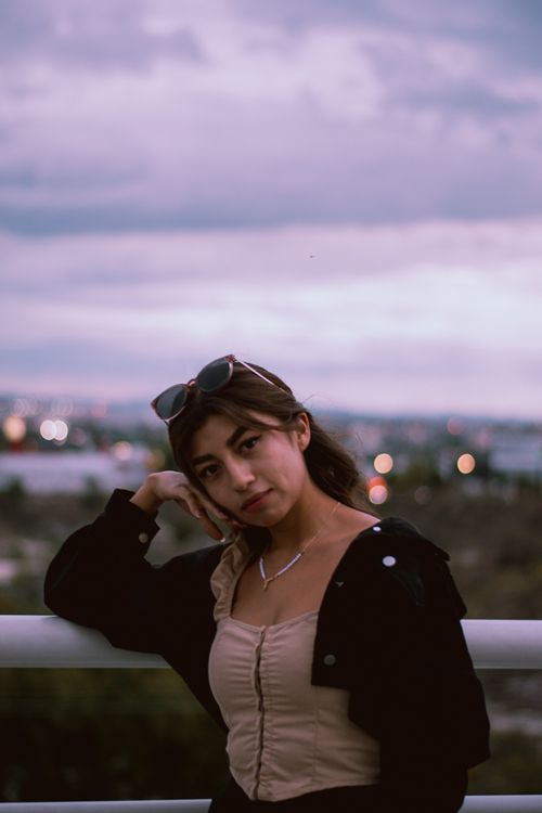 Free A woman posing casually on a balcony during the evening golden hour. Stock Photo