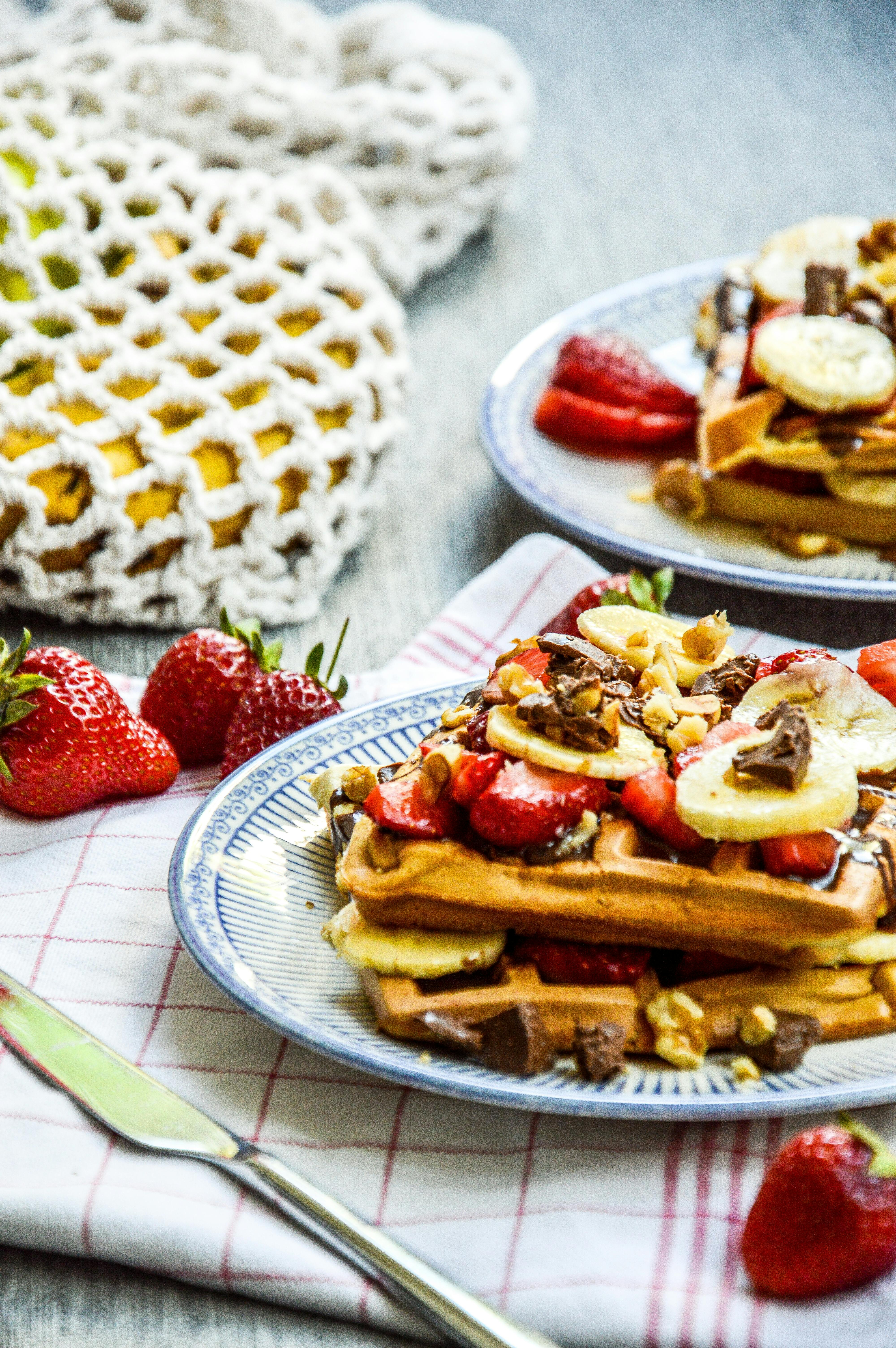 Mouthwatering Belgian waffles topped with fresh strawberries, bananas, and nuts, perfect for breakfast.