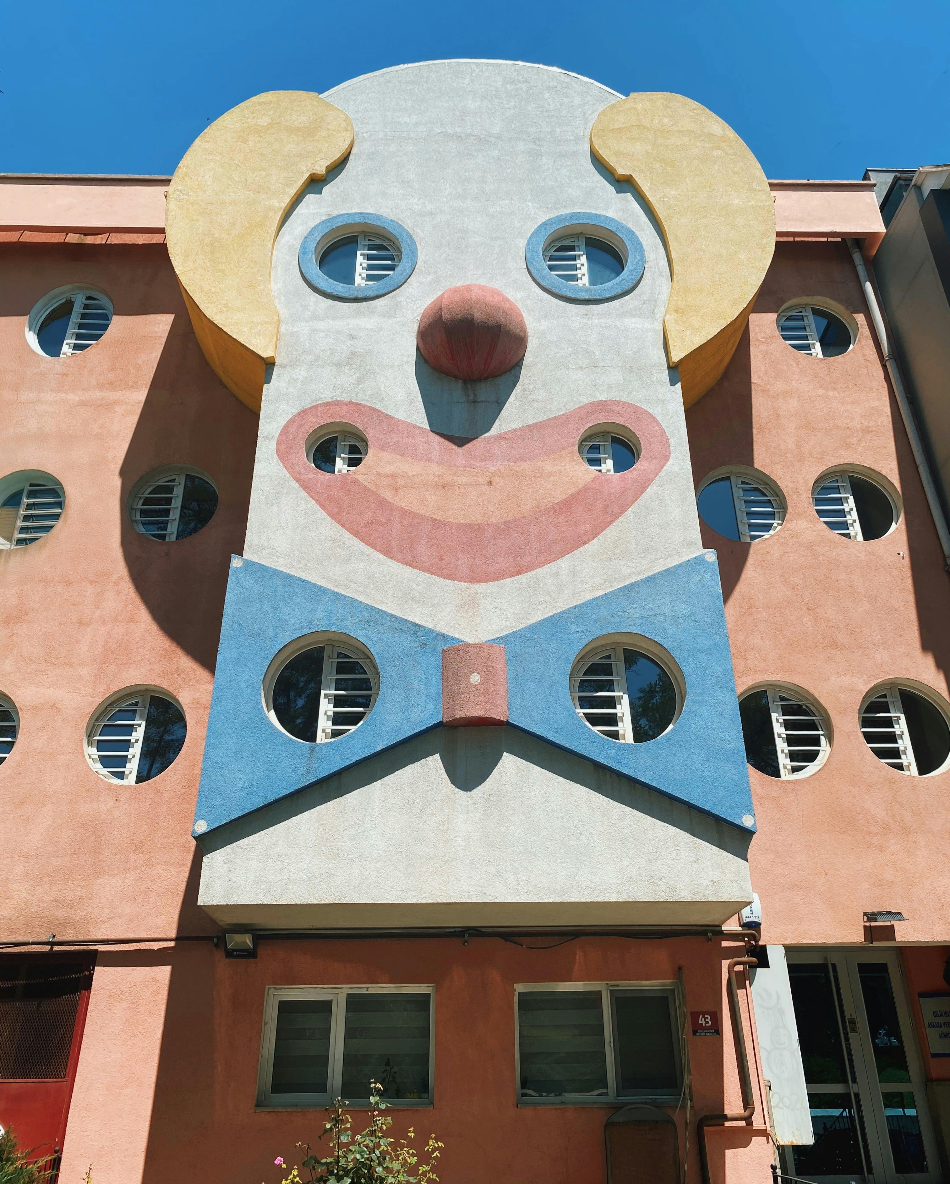 A vibrant building with clown face design in Ankara, Türkiye, featuring circular windows.