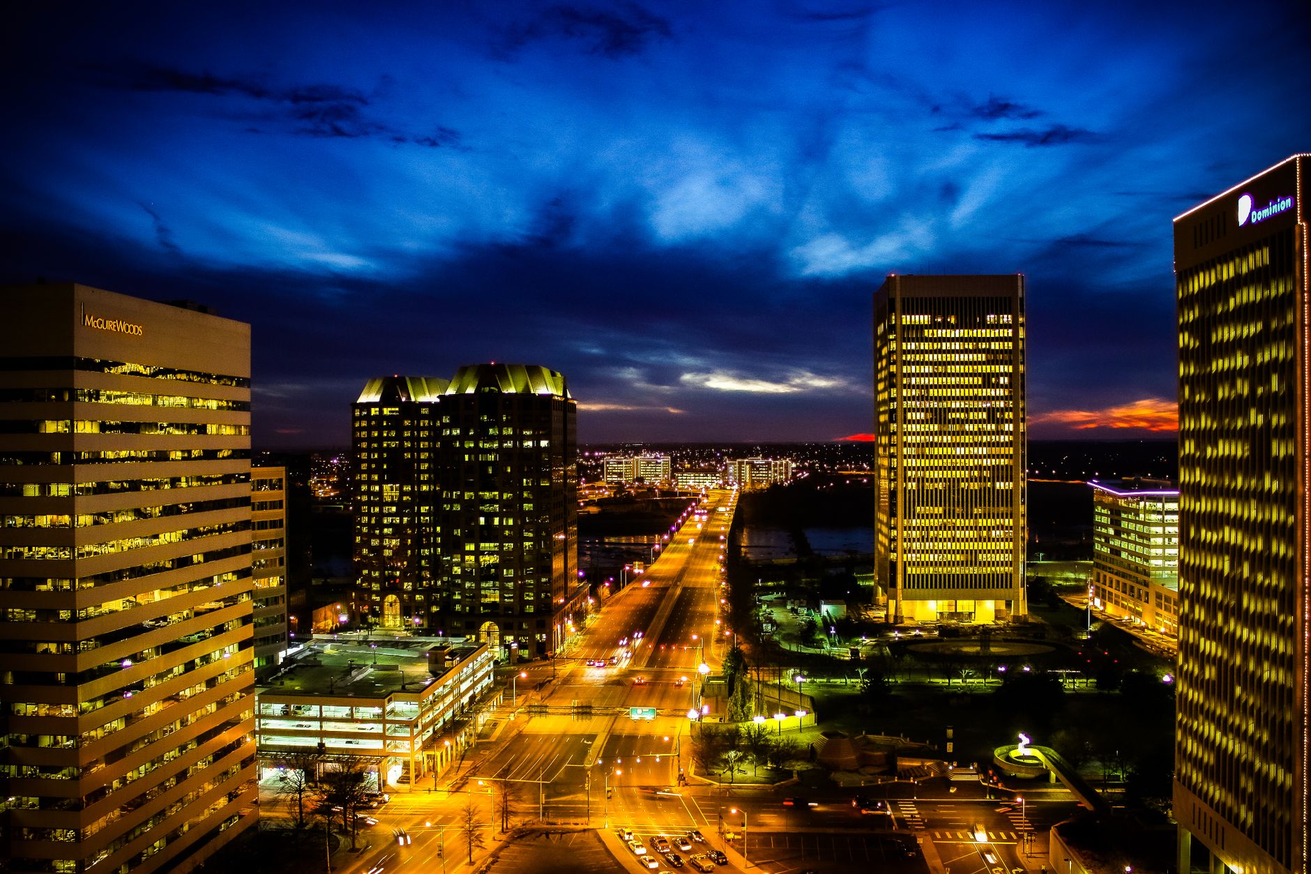 A stunning view of Richmond, Virginia's skyline during twilight with illuminated buildings and vibrant blue sky.