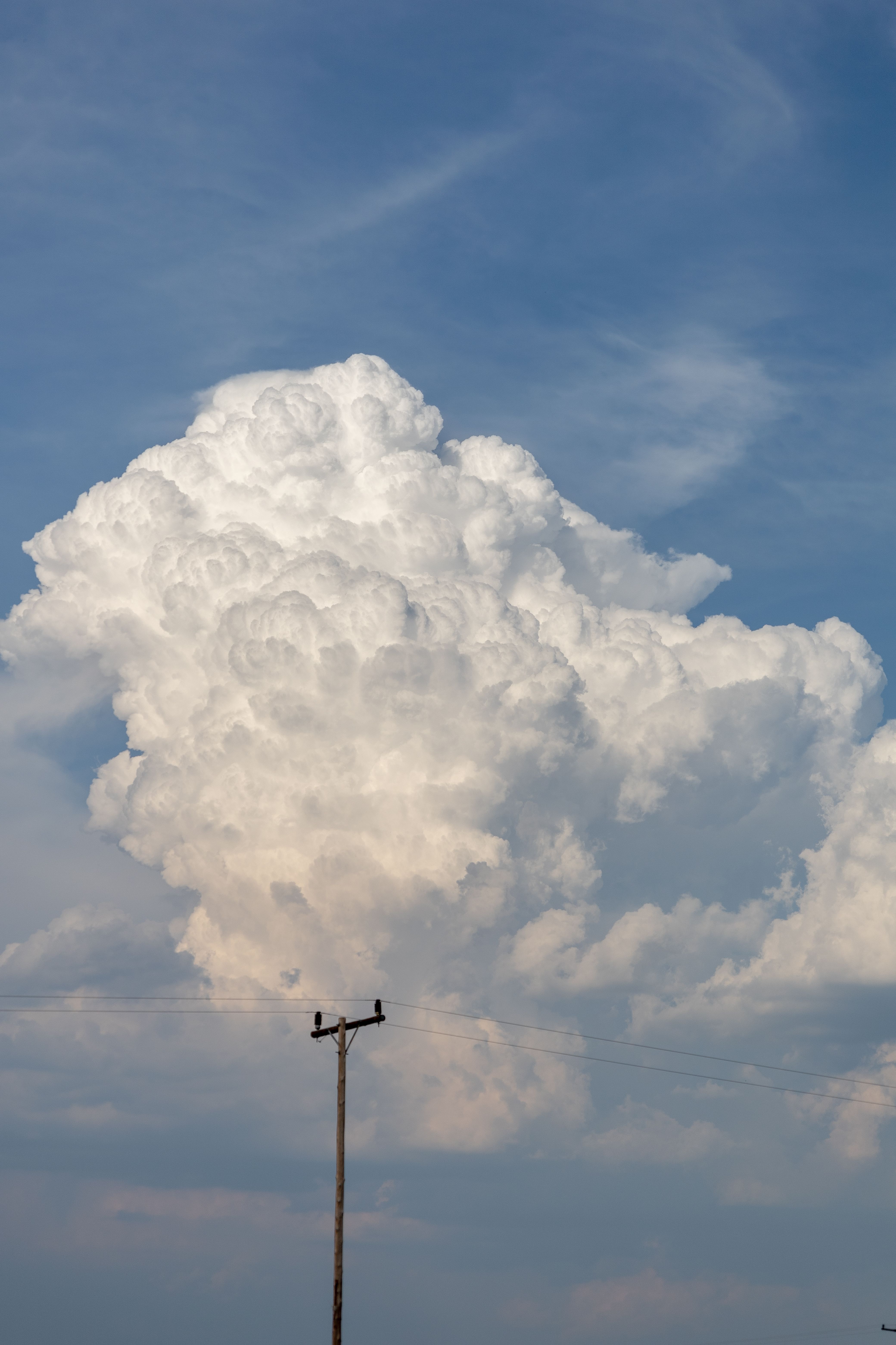 Dramatic cumulus clouds tower above a power line in Ephangweni, South Africa.