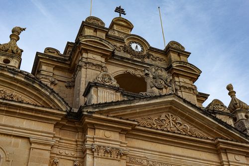 Free Intricate Baroque church facade with detailed carvings and clock, located in Malta. Stock Photo