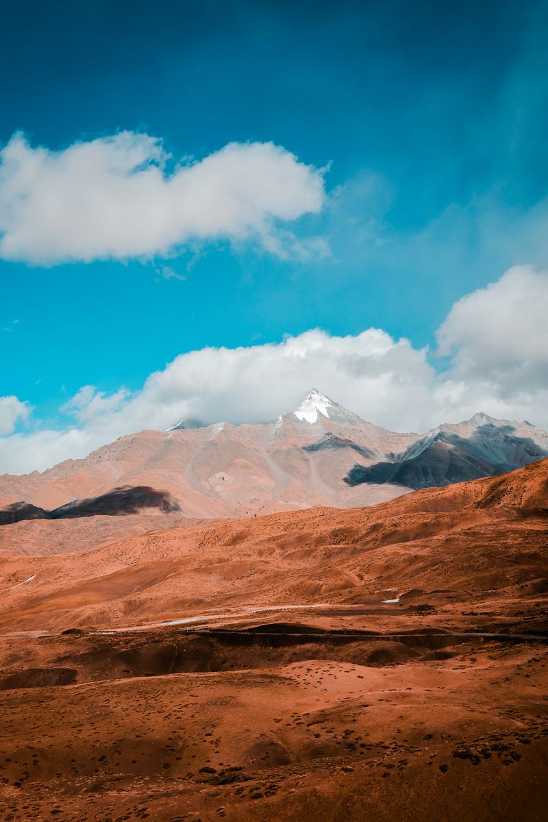 Breathtaking view of snow-capped mountains in Spiti Valley under a vibrant blue sky.