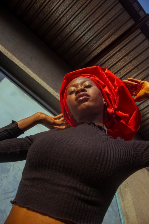 Free Artistic portrait of a woman with a red headscarf in urban setting. Stock Photo