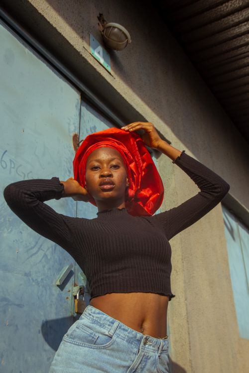 Free Confident young woman in a black top and red headscarf posing outdoors in sunlight. Stock Photo