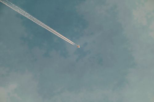 Free Minimalist shot of an airplane with contrail in a clear blue sky, symbolizing freedom. Stock Photo