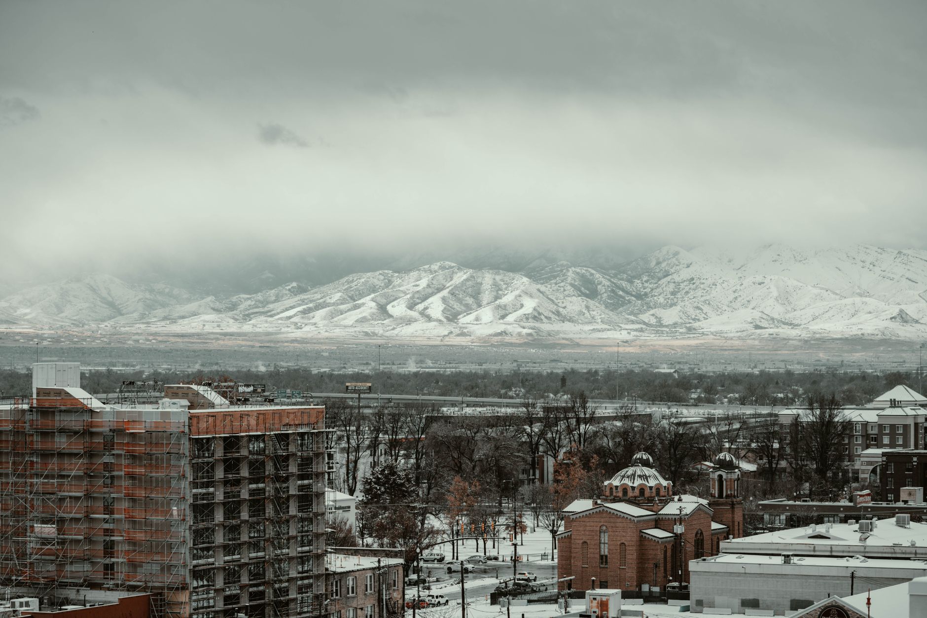 A snowy urban landscape of Salt Lake City with mountain backdrop captured in winter.