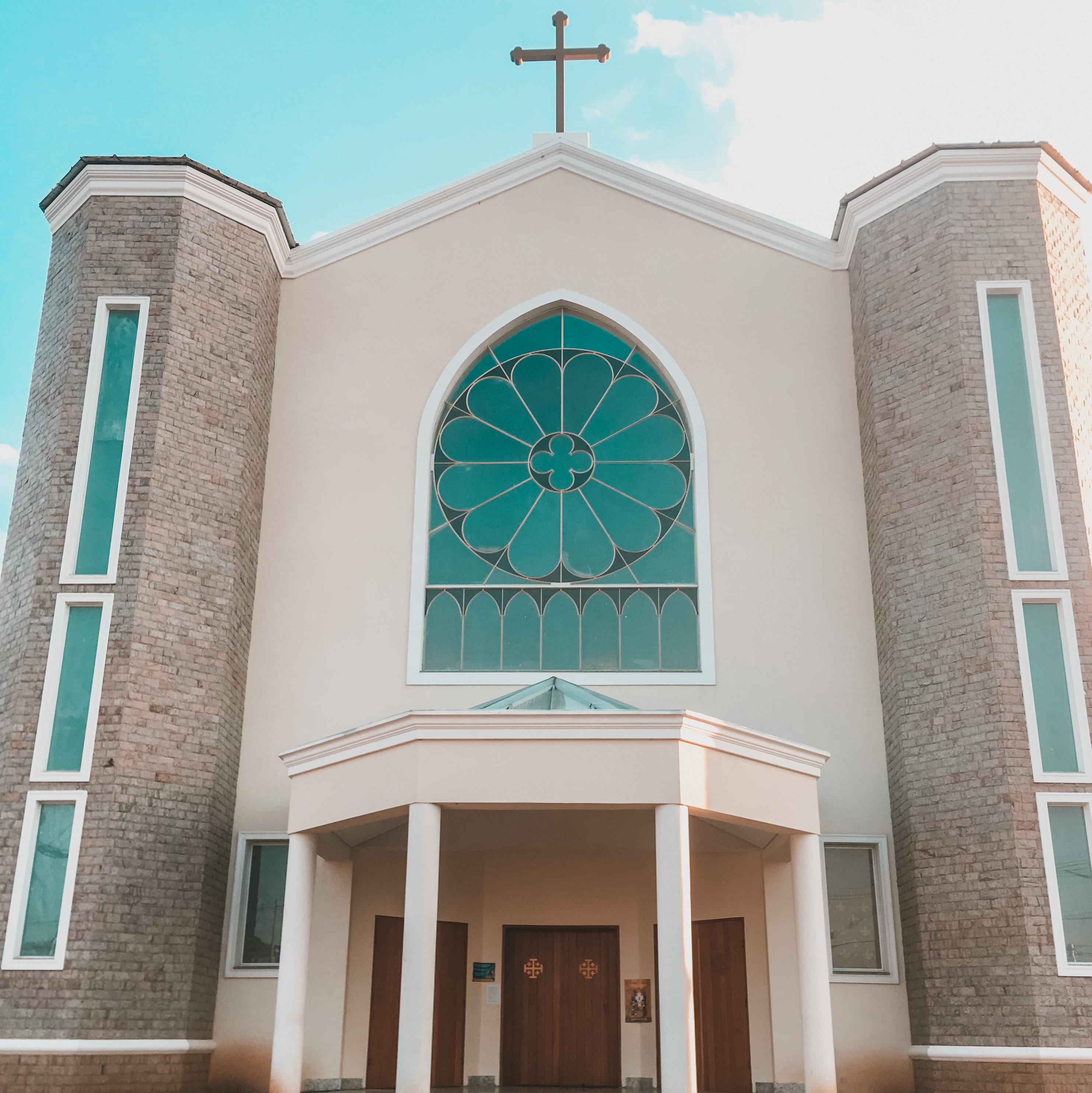 在日光下拍摄的教堂立面，配有彩色玻璃和十字架，十分美丽
