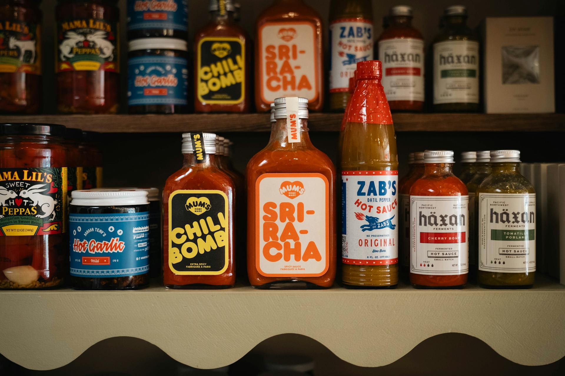 A variety of hot sauces and spices neatly arranged on a store shelf, showcasing diverse flavors.