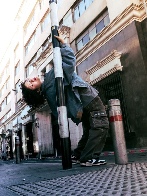 Free A young adult bending back on a pole in urban street setting. Stock Photo