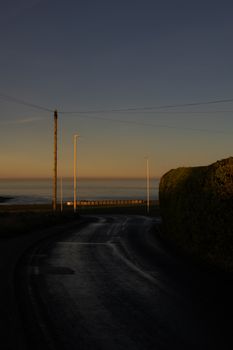 A serene coastal road at twilight in England, capturing the tranquil atmosphere with sea view.