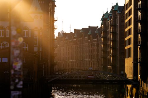 Free Golden sunset over a historic warehouse district with a canal and bridge. Stock Photo