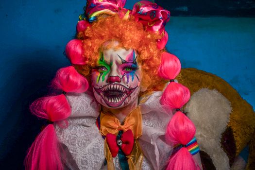 A vibrant portrait of a clown with colorful makeup and bright pink hair, exuding a dramatic artistic style.