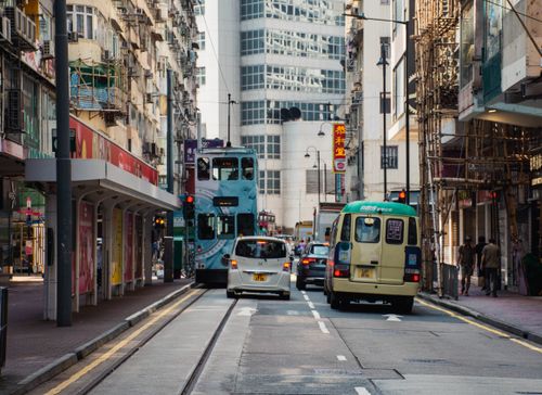 Free Hong Kong street scene with trams and vehicles in bright daylight. Stock Photo