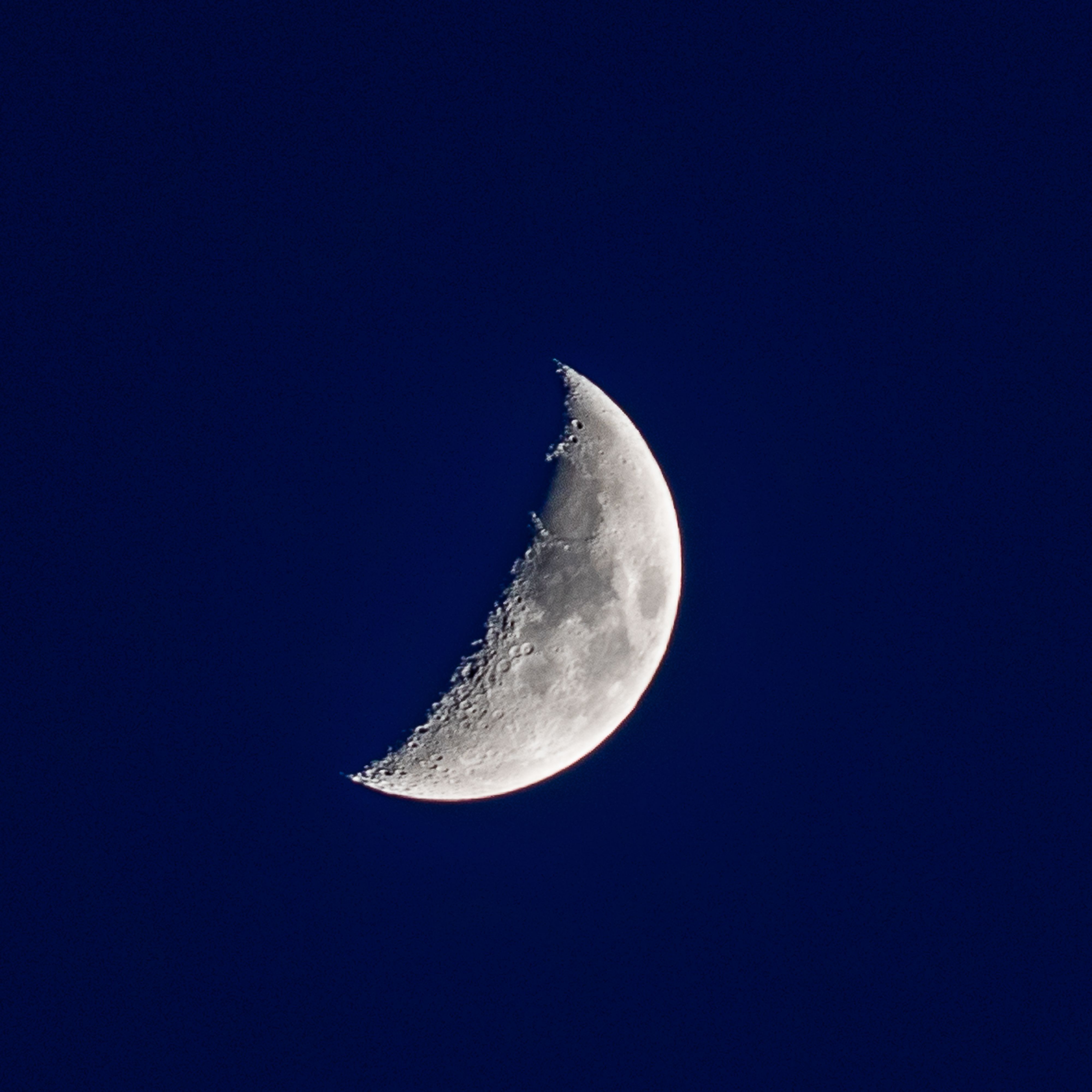 Crescent moon in a deep blue night sky — photo by Vũ Bụi on Pexels