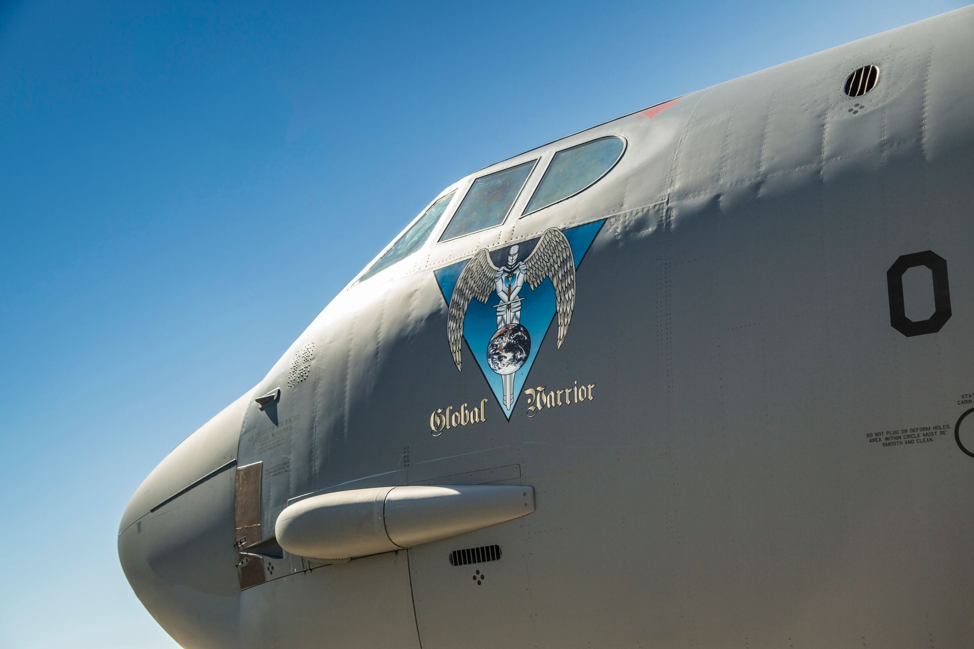A detailed side view of a military aircraft cockpit with 'Global Warrior' insignia, sunny day.