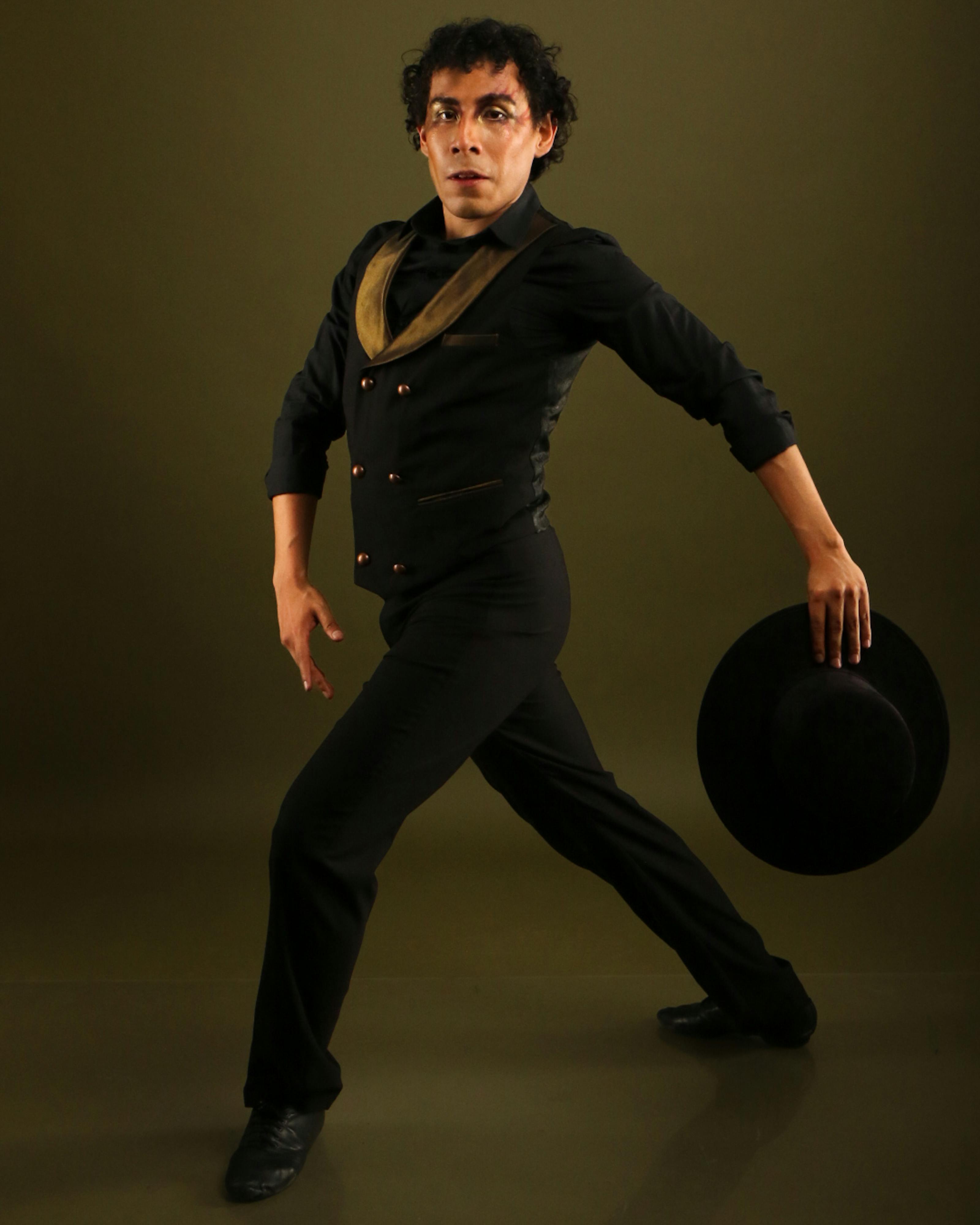 A talented flamenco dancer strikes an elegant pose holding a traditional hat.