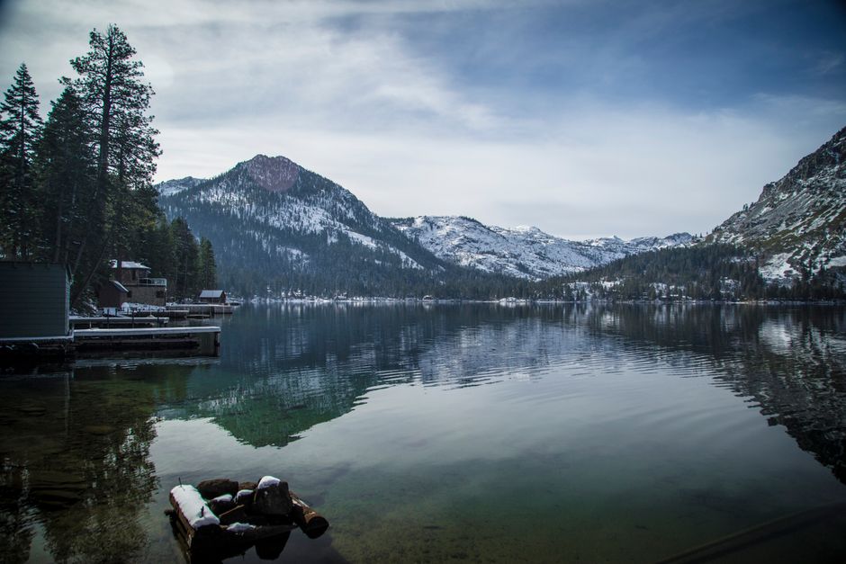 Tranquil view of snow-capped mountains and Lake Tahoe, reflecting a peaceful winter setting.