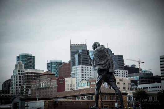 Gandhi statue with San Francisco skyline in background, cloudy day.