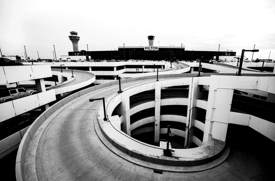 Dramatic black and white view of a spiral parking ramp at Chicago's O'Hare Airport with Hilton hotel in background.