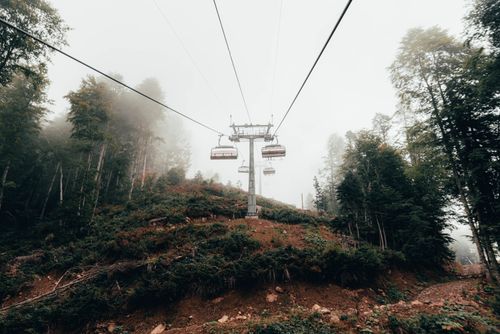 Free Misty mountain scene with cable cars and forest, perfect for travel and nature themes. Stock Photo