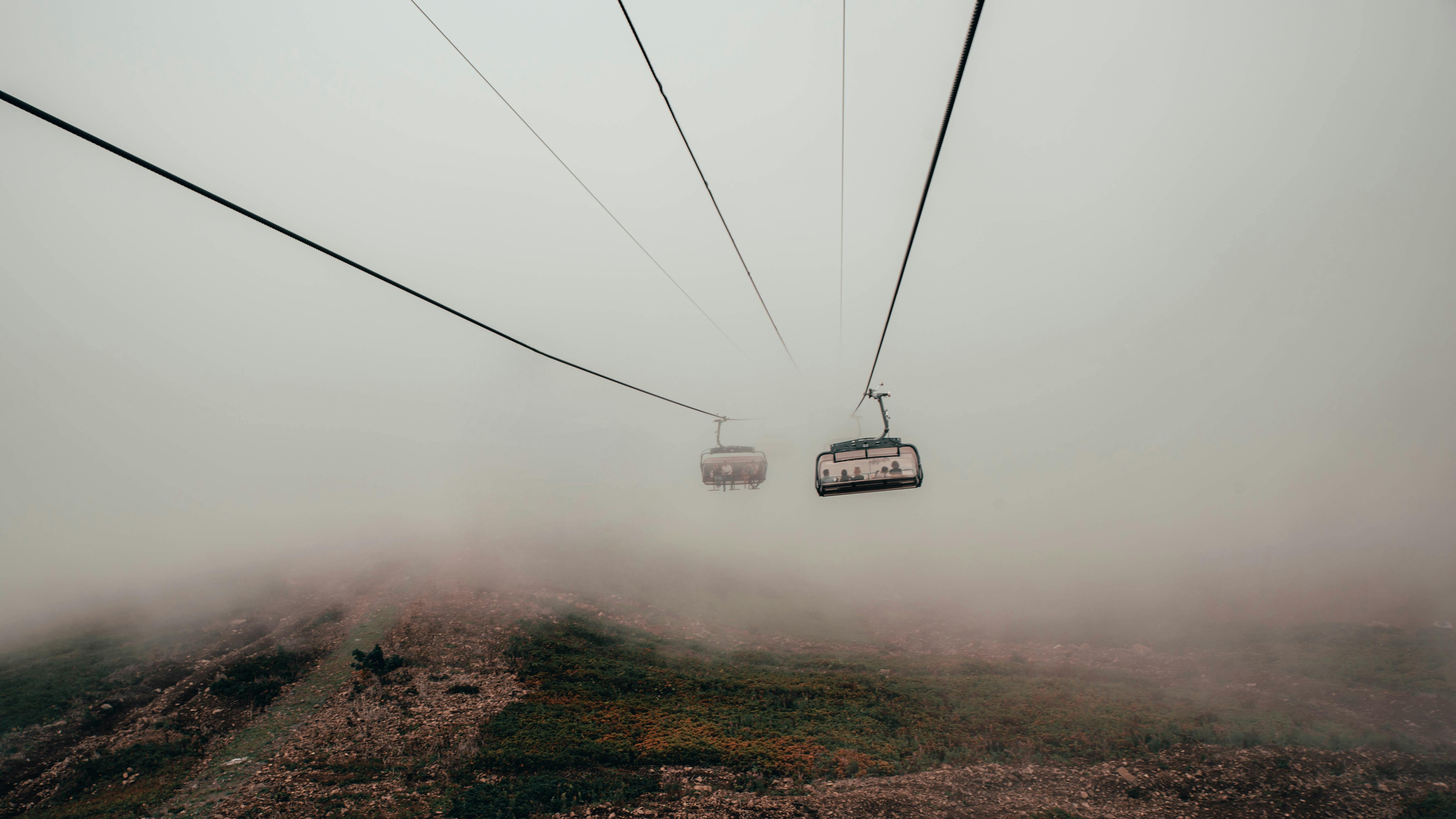 缆车在薄雾笼罩的山区穿行，于浓雾中移动，营造出宁静而神秘的氛围